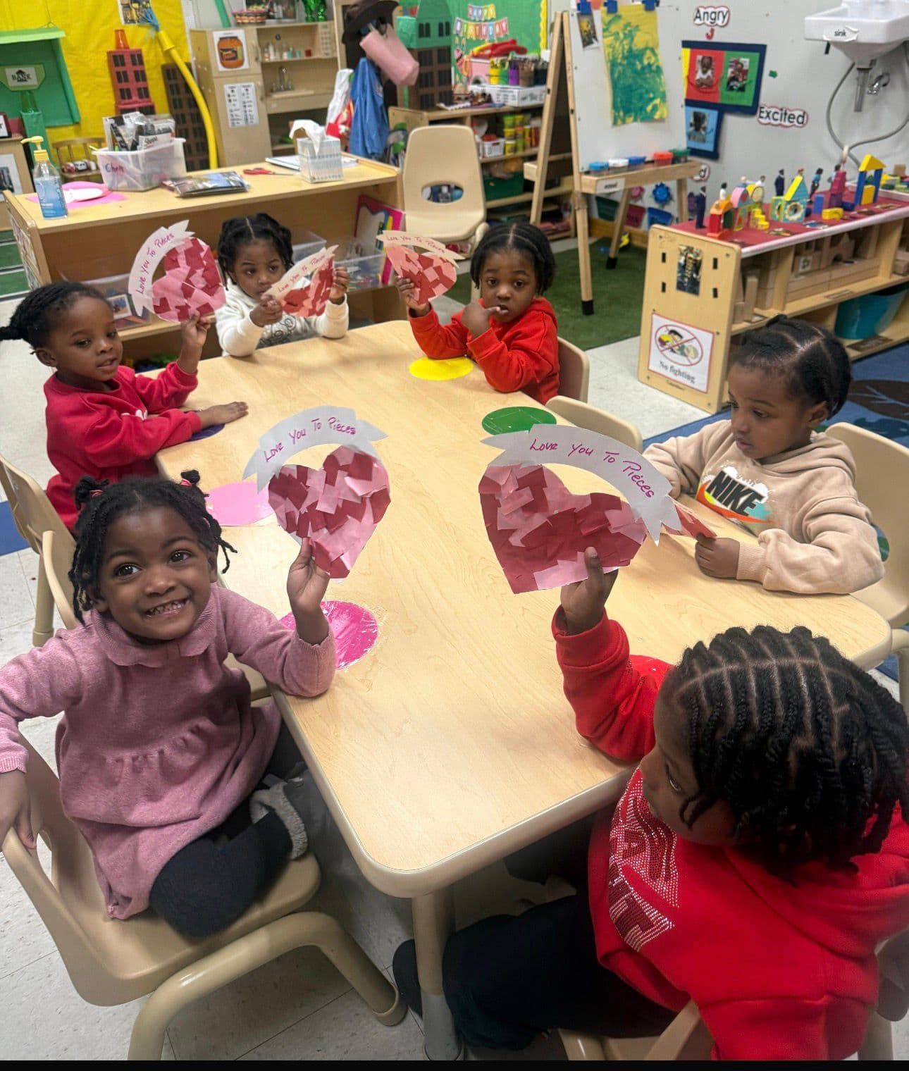 Children proudly showing their Valentine's Day heart art projects
