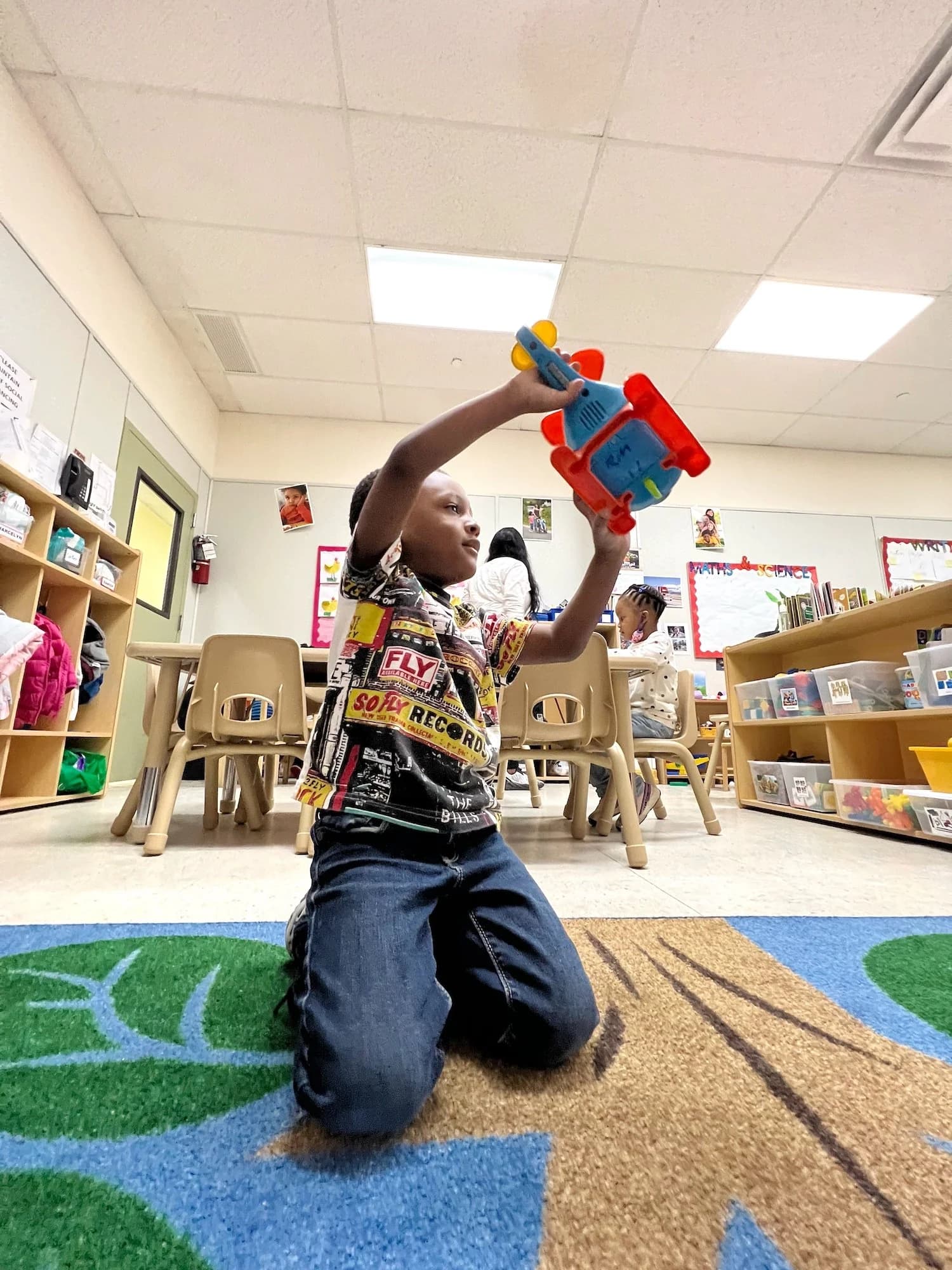 A boy playing with a toy robot during free play time