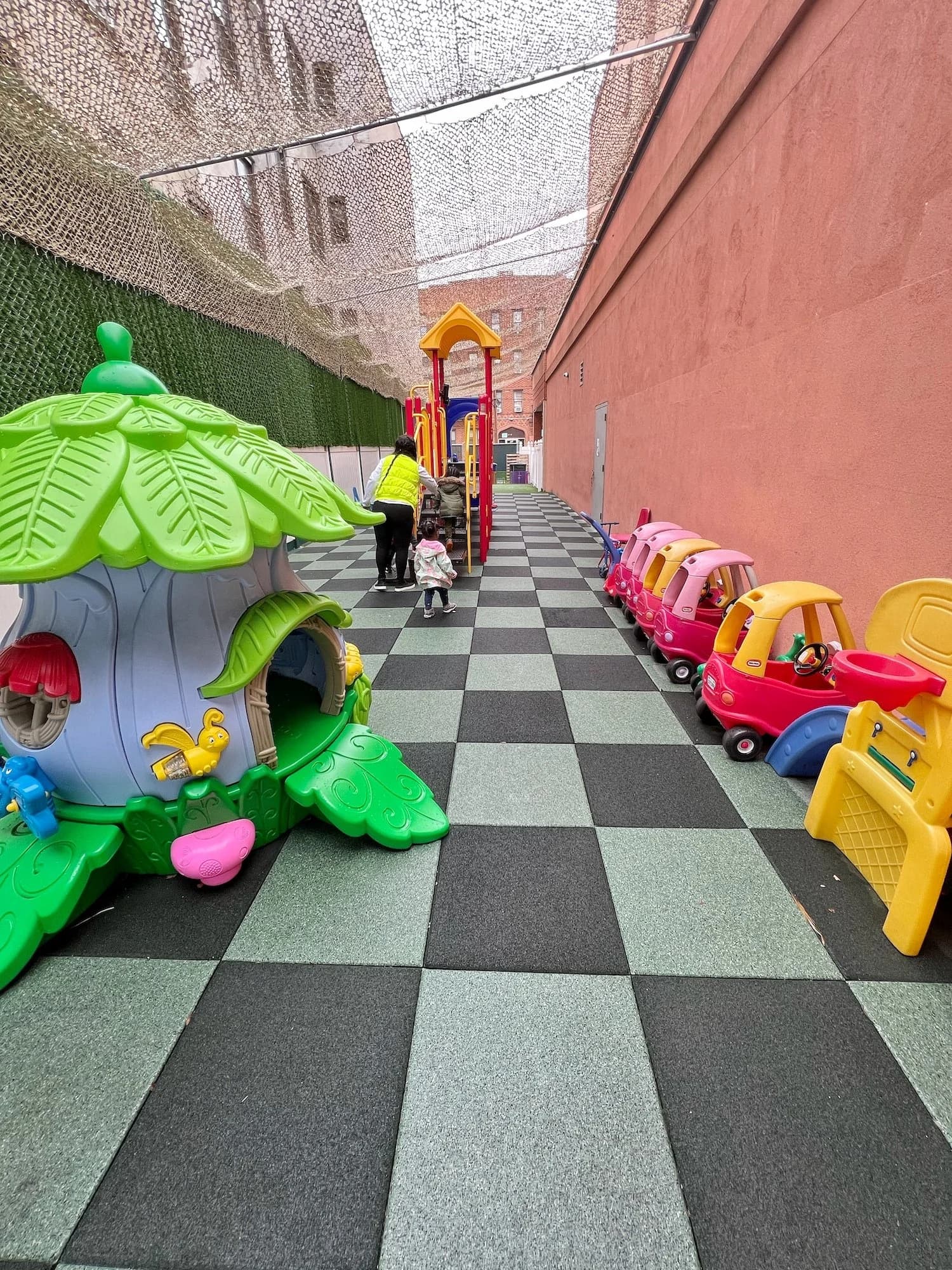 Wide view of the covered outdoor play area with colorful equipment and safety flooring