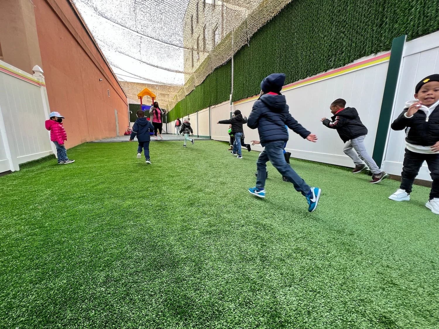 Children running freely across the outdoor turf play area