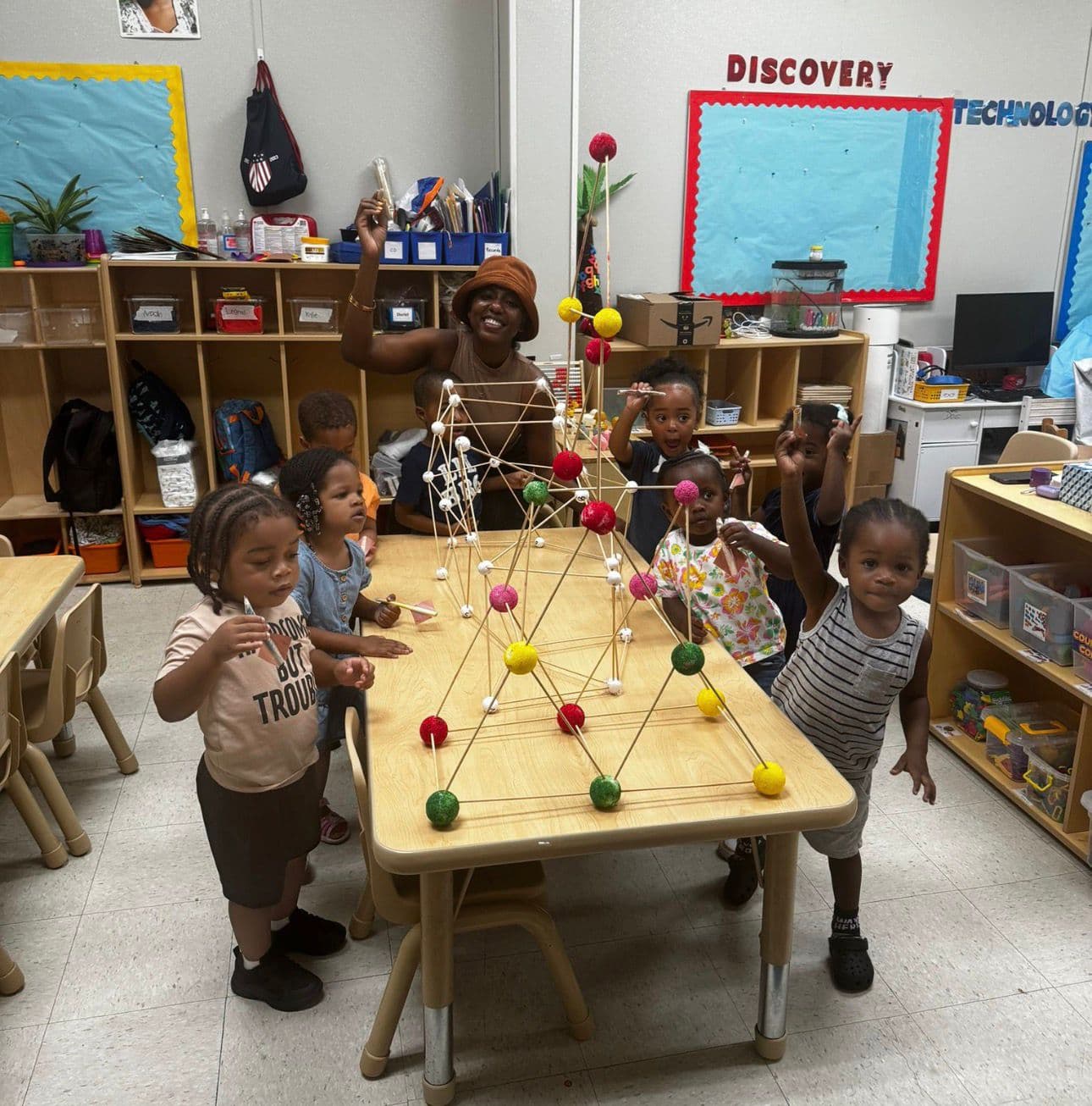 Teacher and children building a large geometric structure during a STEM activity